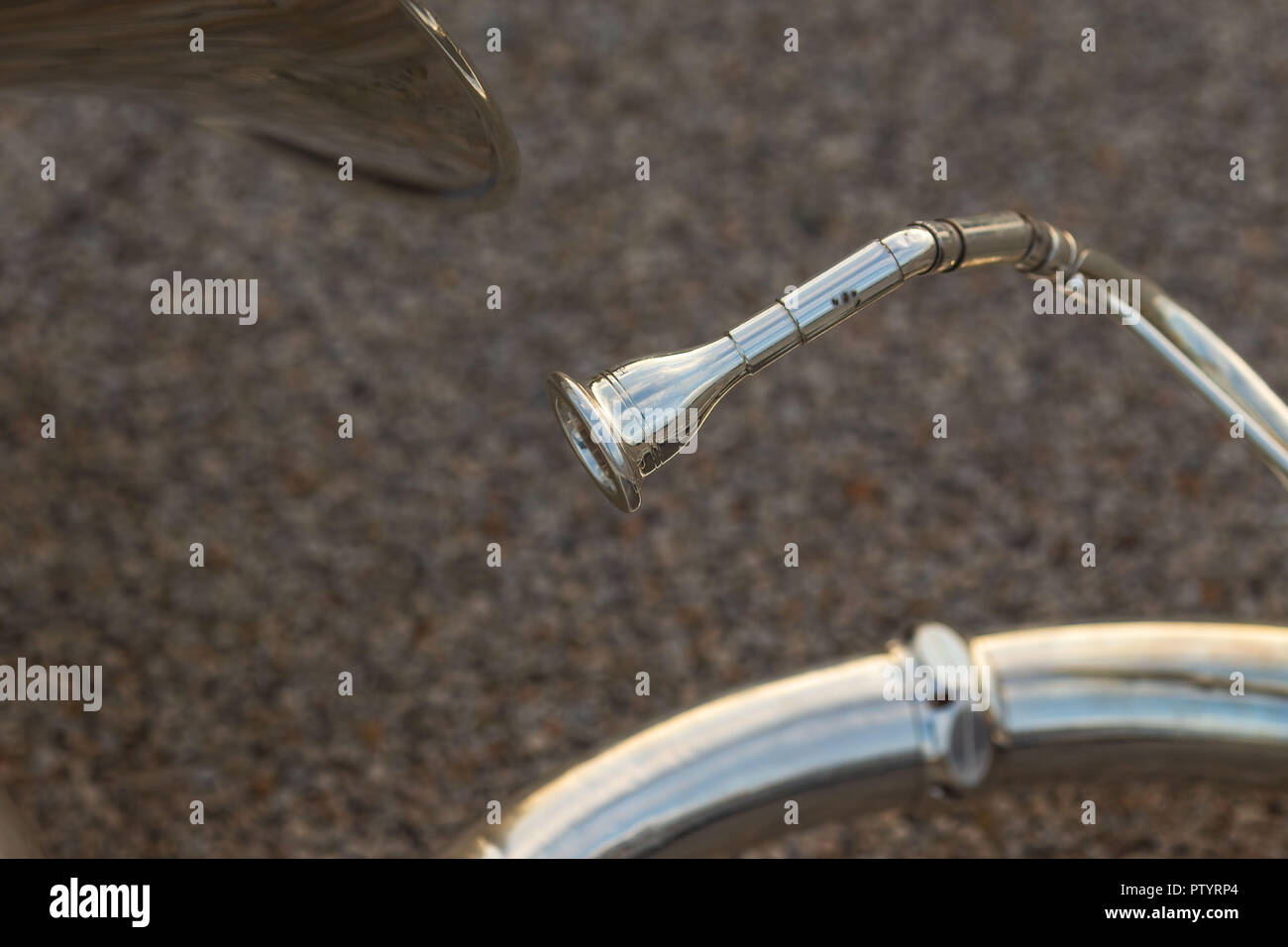 a close up of the mouthpiece of a sousaphone resting on the ground during a marching band rehearsal Stock Photo