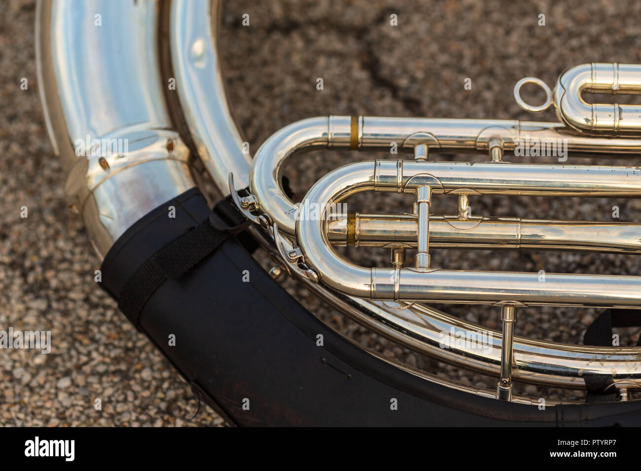 a well used sousaphone resting on the ground during a marching band rehearsal Stock Photo