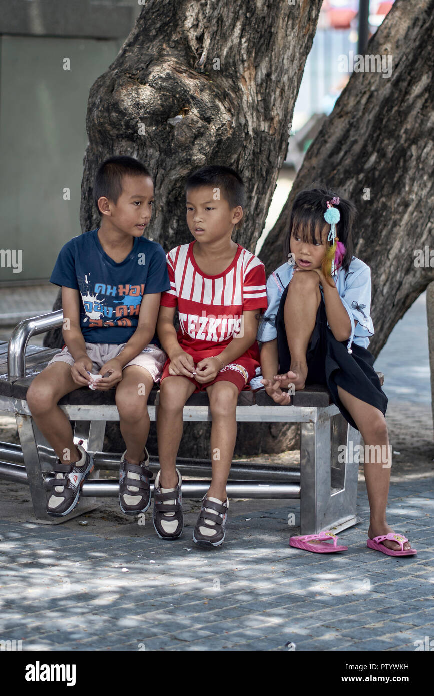 Three young friends sitting on a bench. Thailand Southeast Asia Stock Photo