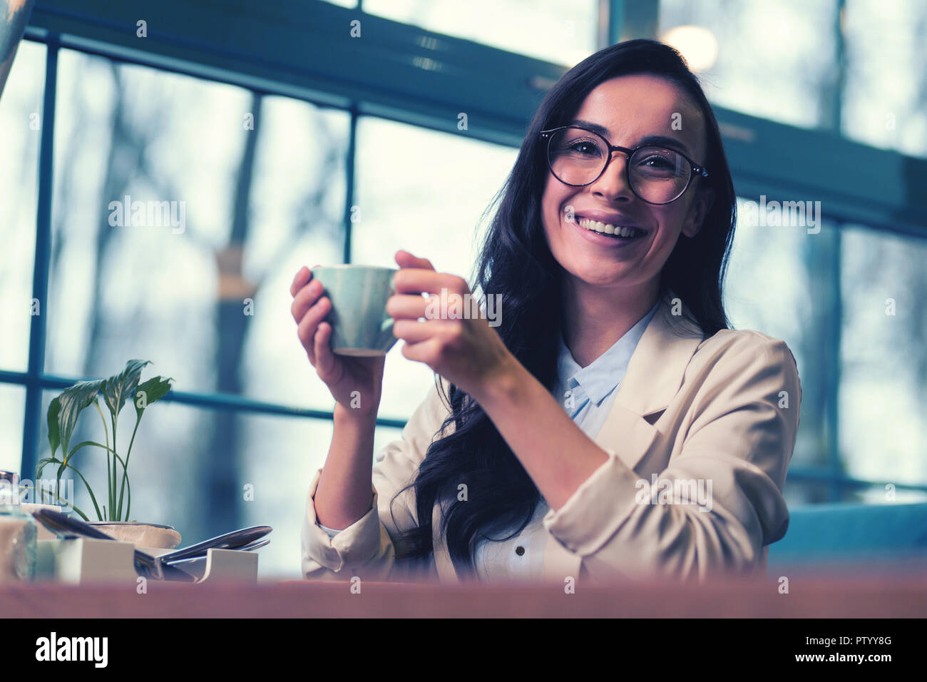 Charming young woman drinking tasty coffee in cafeteria Stock Photo