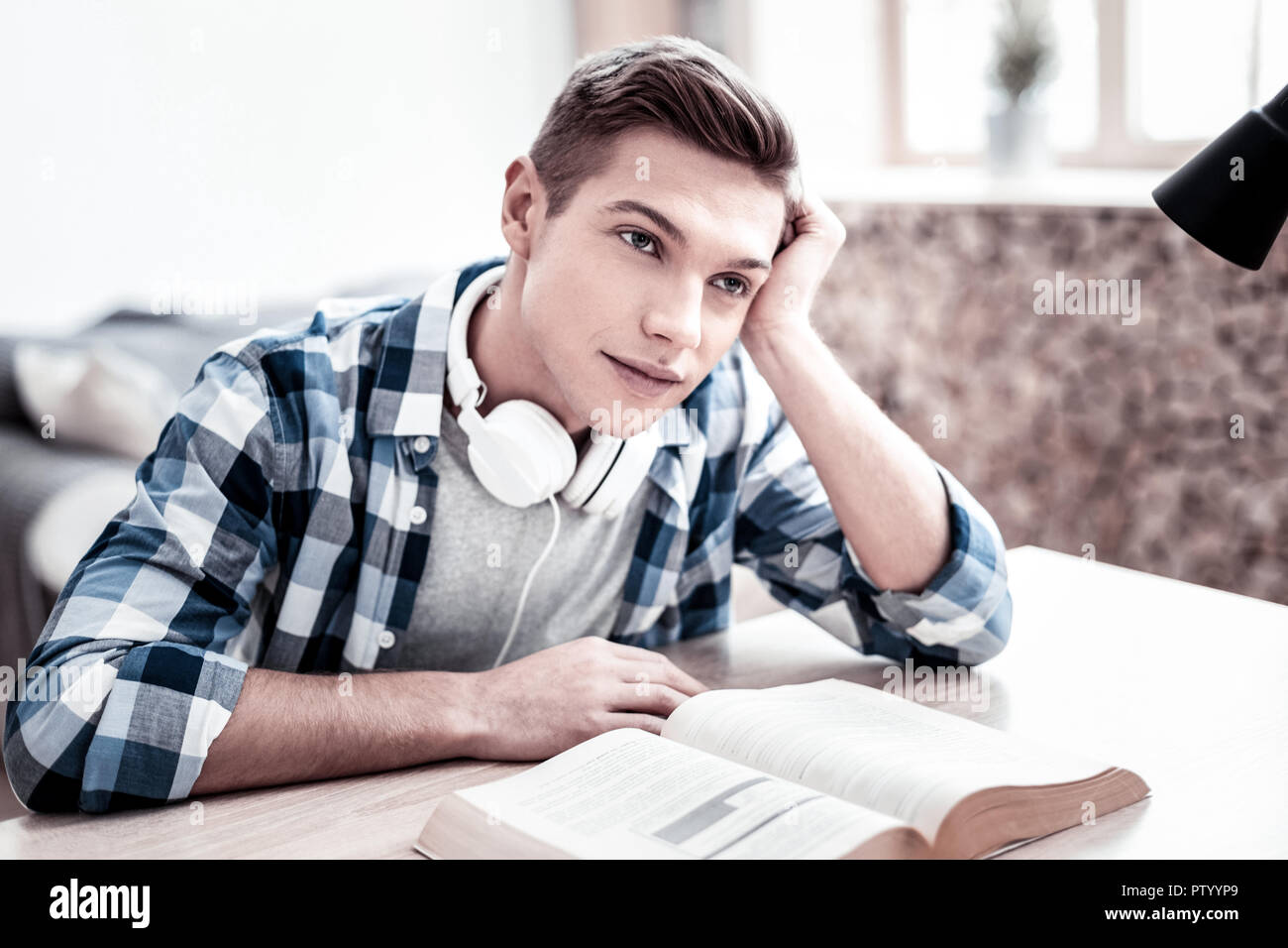 Dreamy student looking tired and thoughtfully smiling Stock Photo