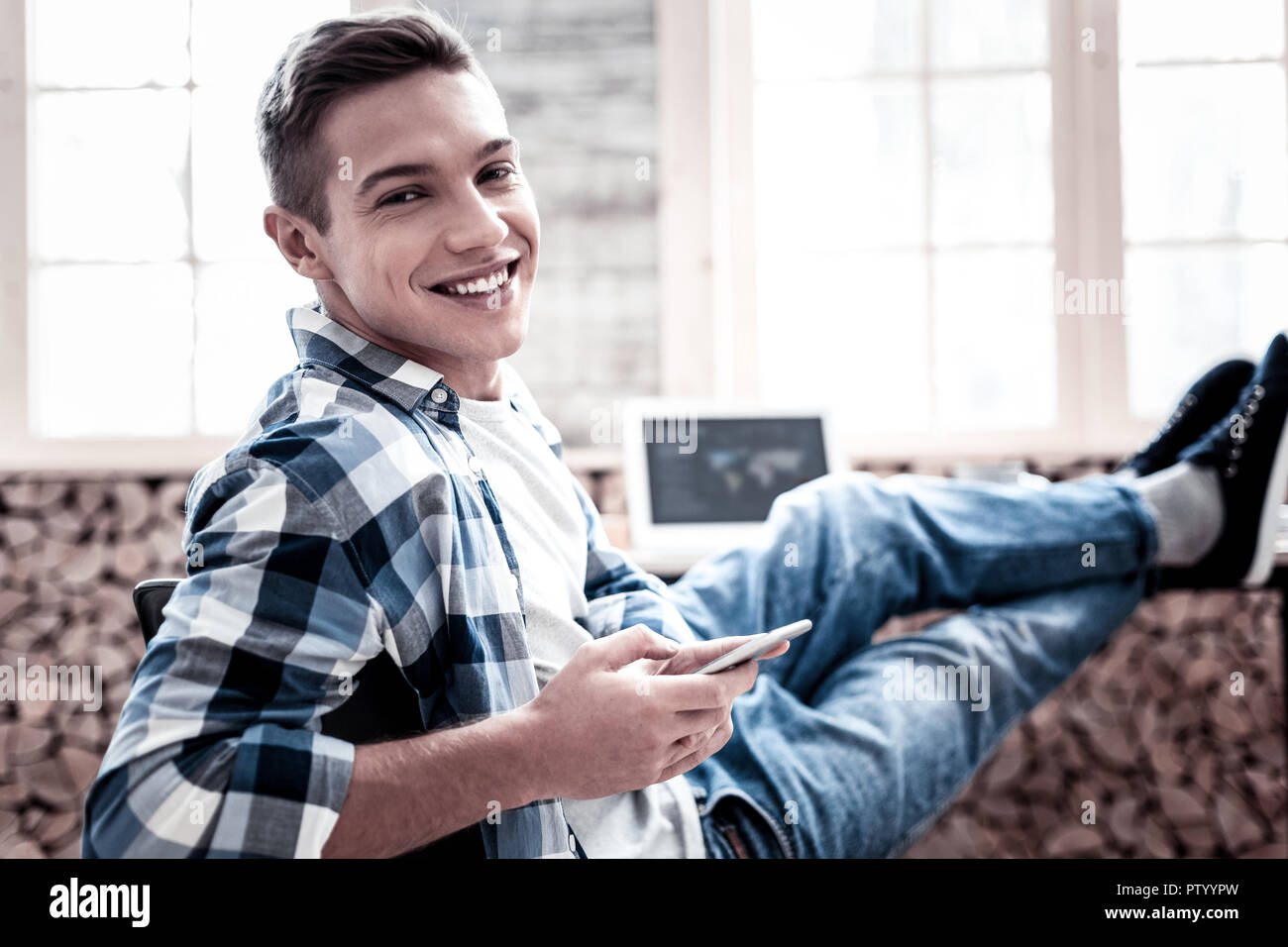 Positive young man putting his feet on the sofa while relaxing at home