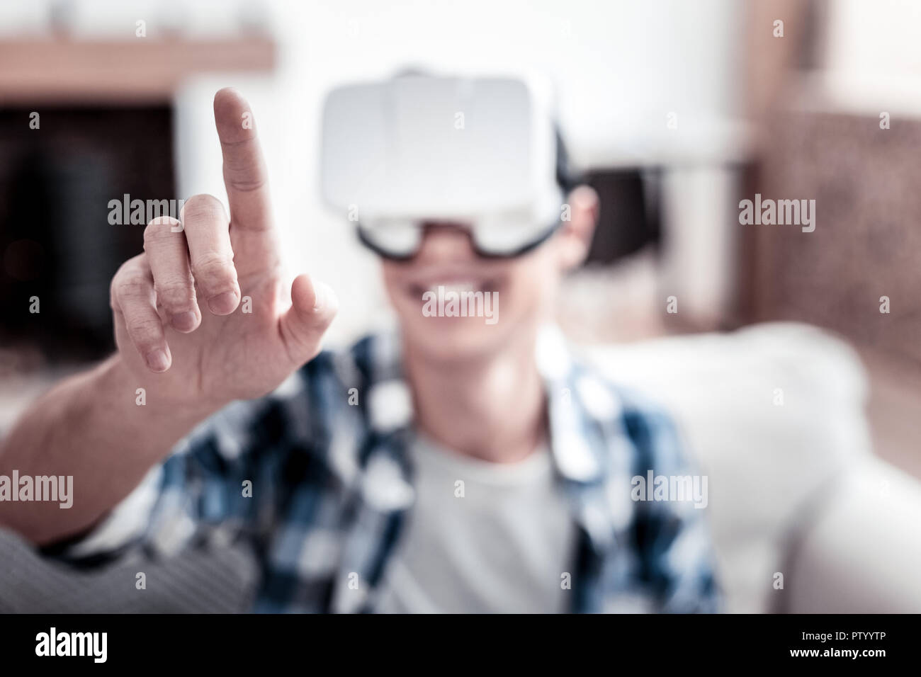 Cheerful man touching transparent screen while using virtual reality glasses Stock Photo