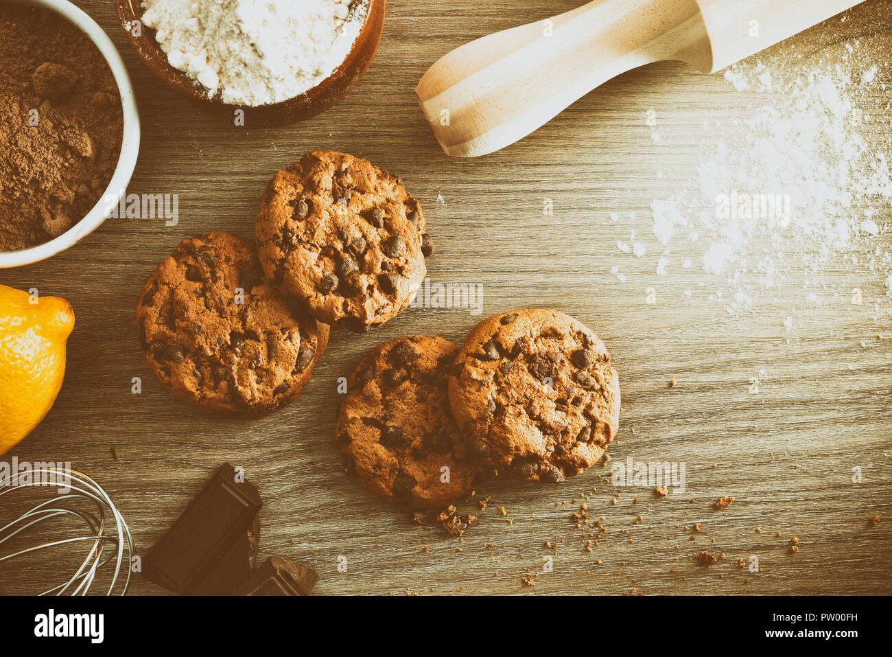 Homemade cookies with chocolate chips on wooden table with ingredients in a rustic kitchen vintage. Horizontal composition. Top view Stock Photo