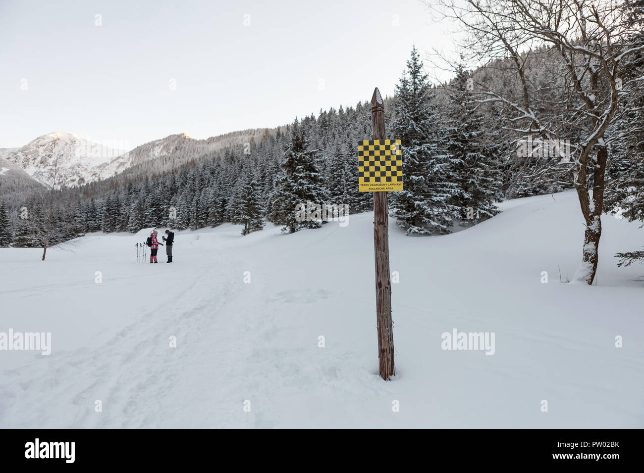 Avalanche area warning sign in english and polish language, valley in Tatra mountains, winter time Stock Photo