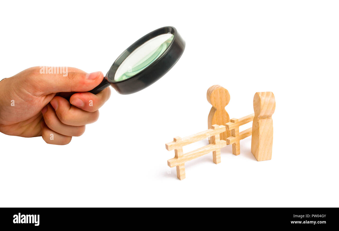 Magnifying glass is looking at the wooden fence divides the two persons discussing the case. Termination and breakdown of relations, breaking ties. Co Stock Photo