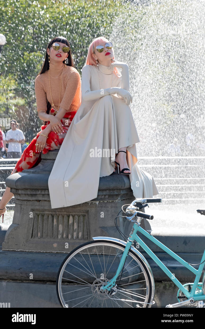 Two beautiful slender Japanese models on a fashion photo shoot near the fountain in Washington Square Park in Greenwich Village, New York City. Stock Photo