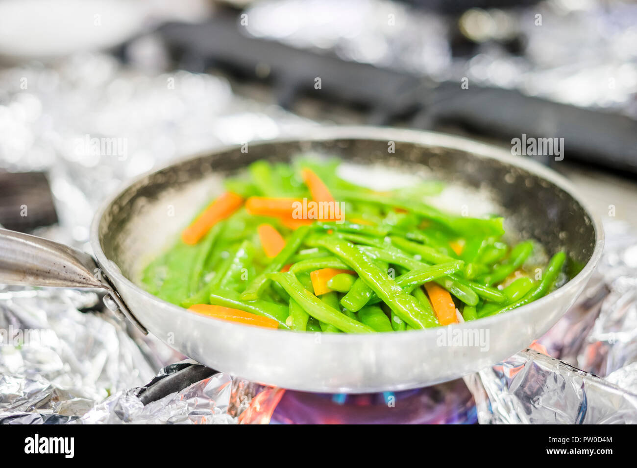 Green beans and carrot fried together on silver pan in the restaurant