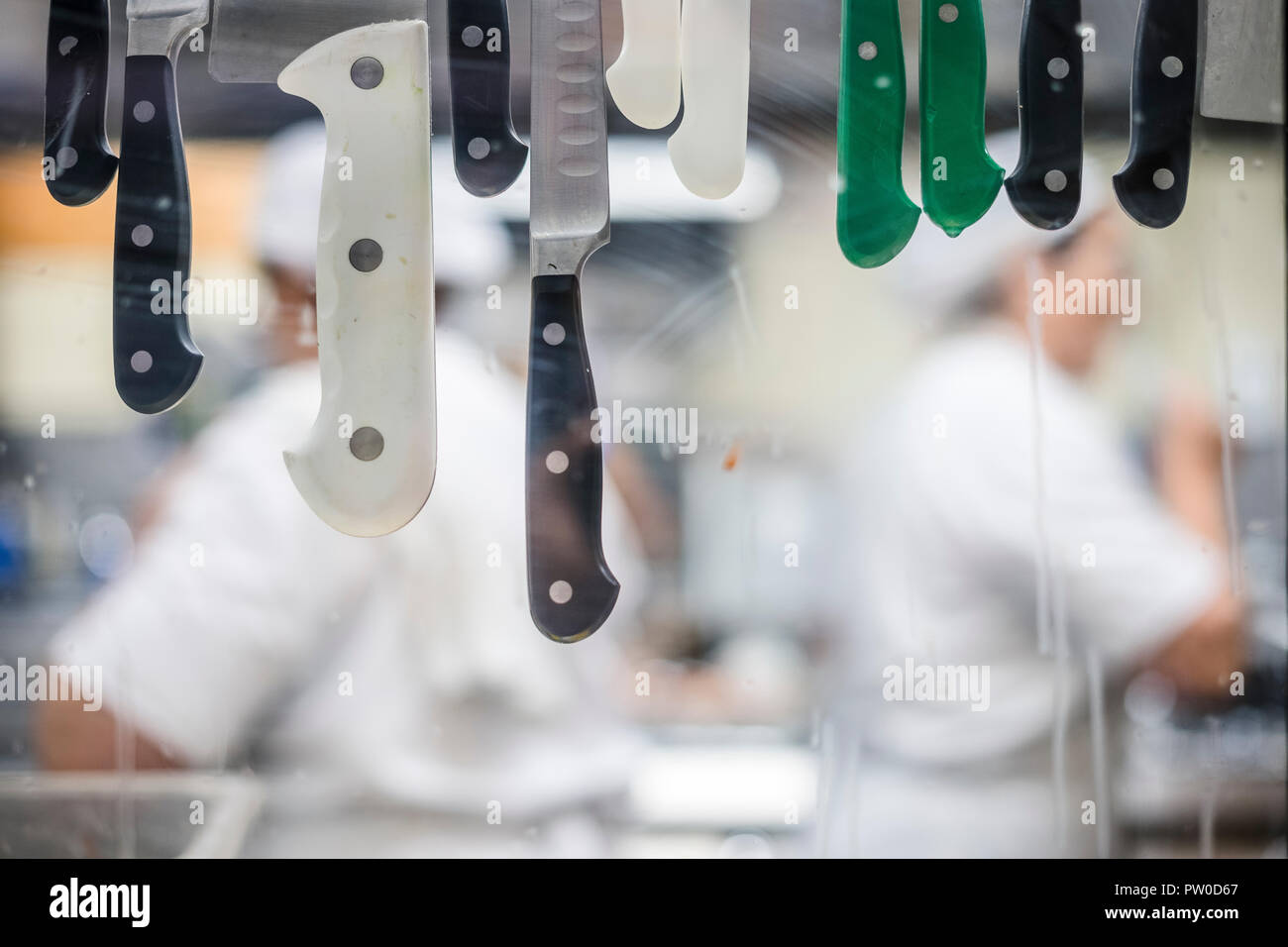 Unfocused restaurant's kitchen workers through window with knifes Stock Photo