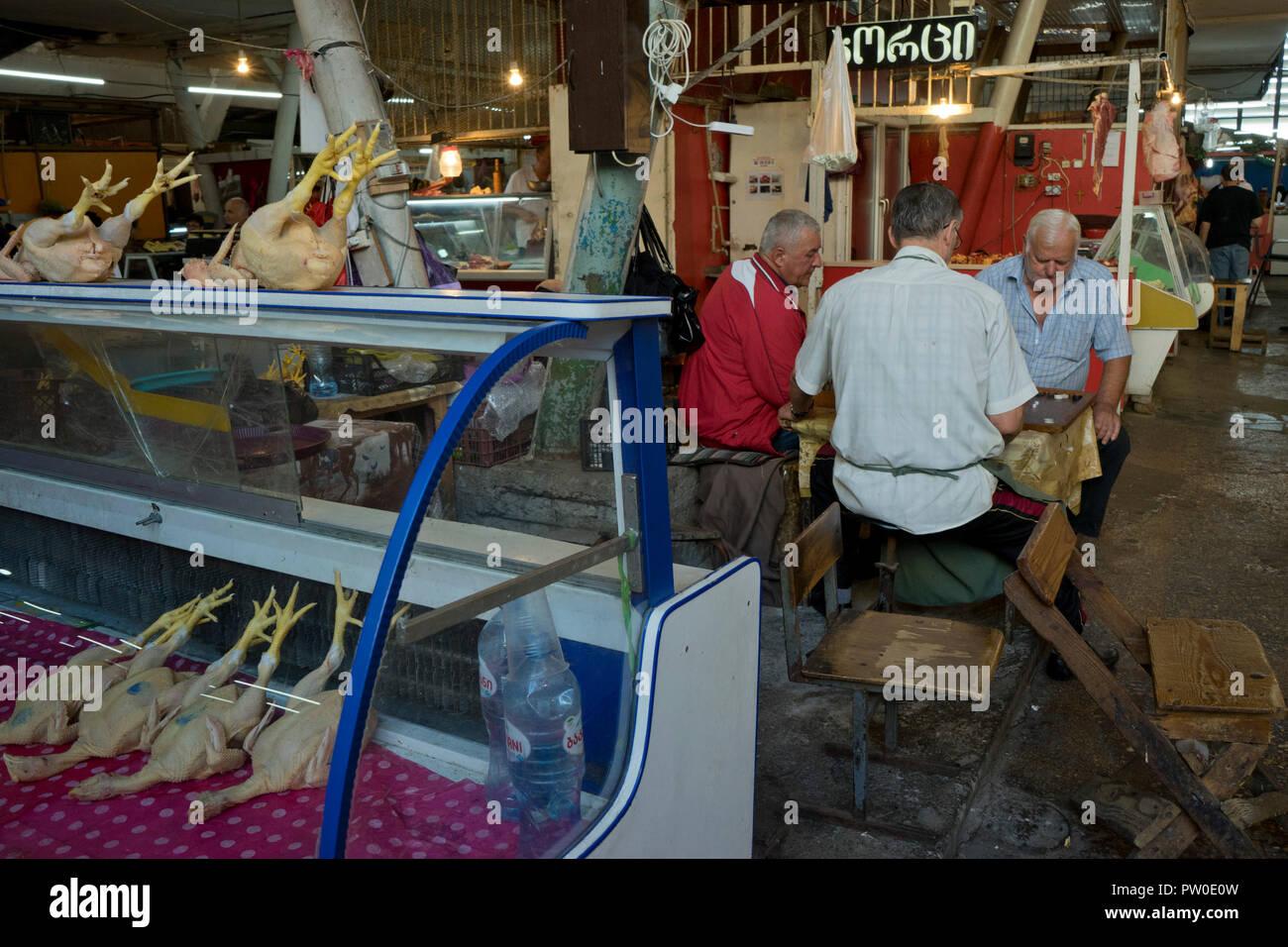 Traders playing backgammon by chicken food counter at the market in ...