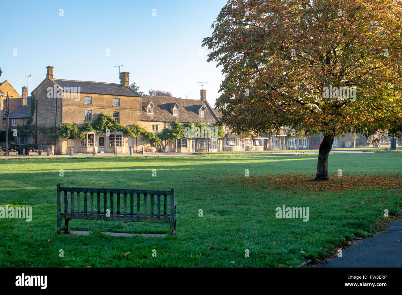 Cotswold shops / houses across from the village green in the early morning autumn sunlight