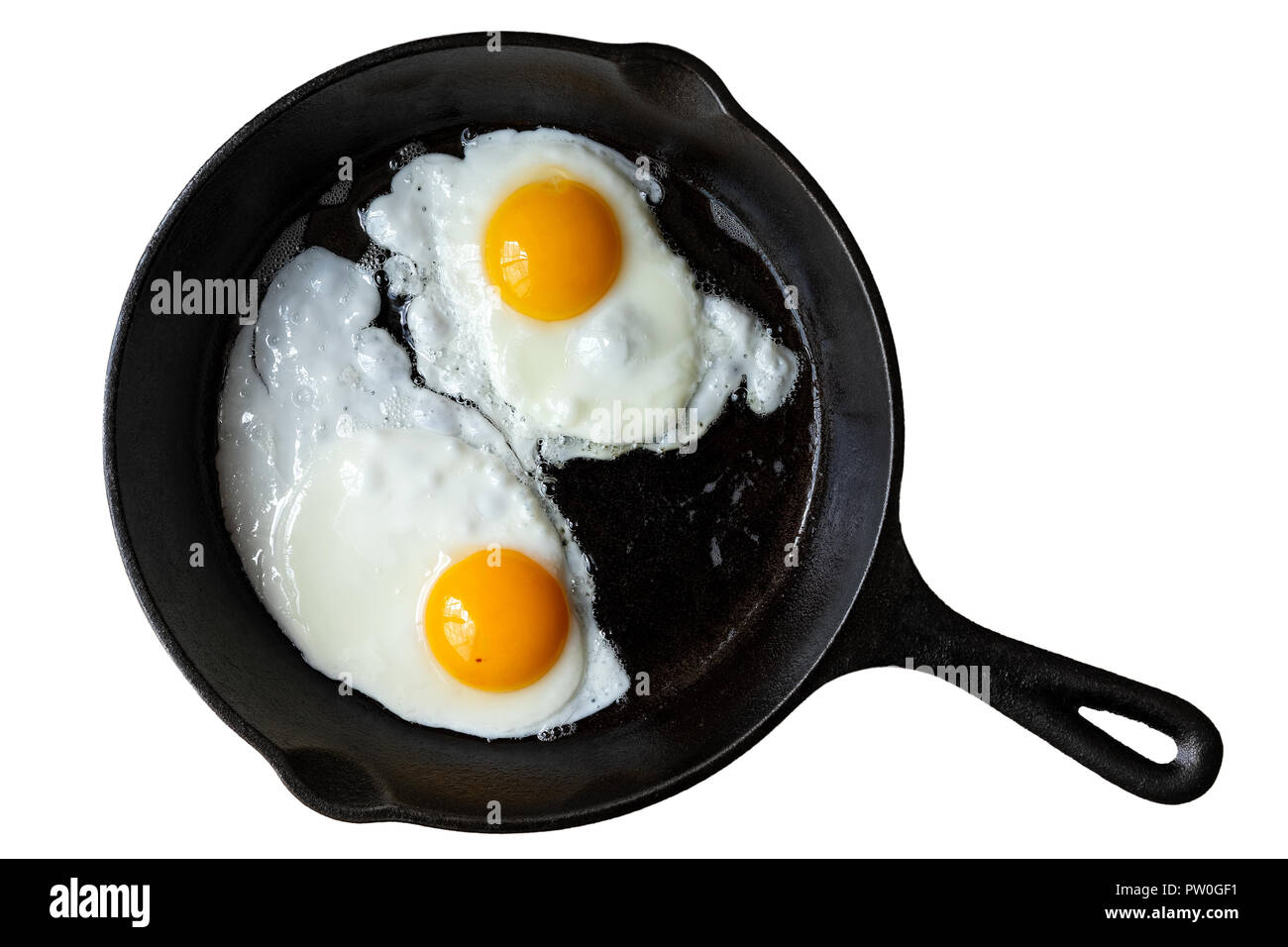 Two fried eggs in cast iron frying pan isolated on white from above