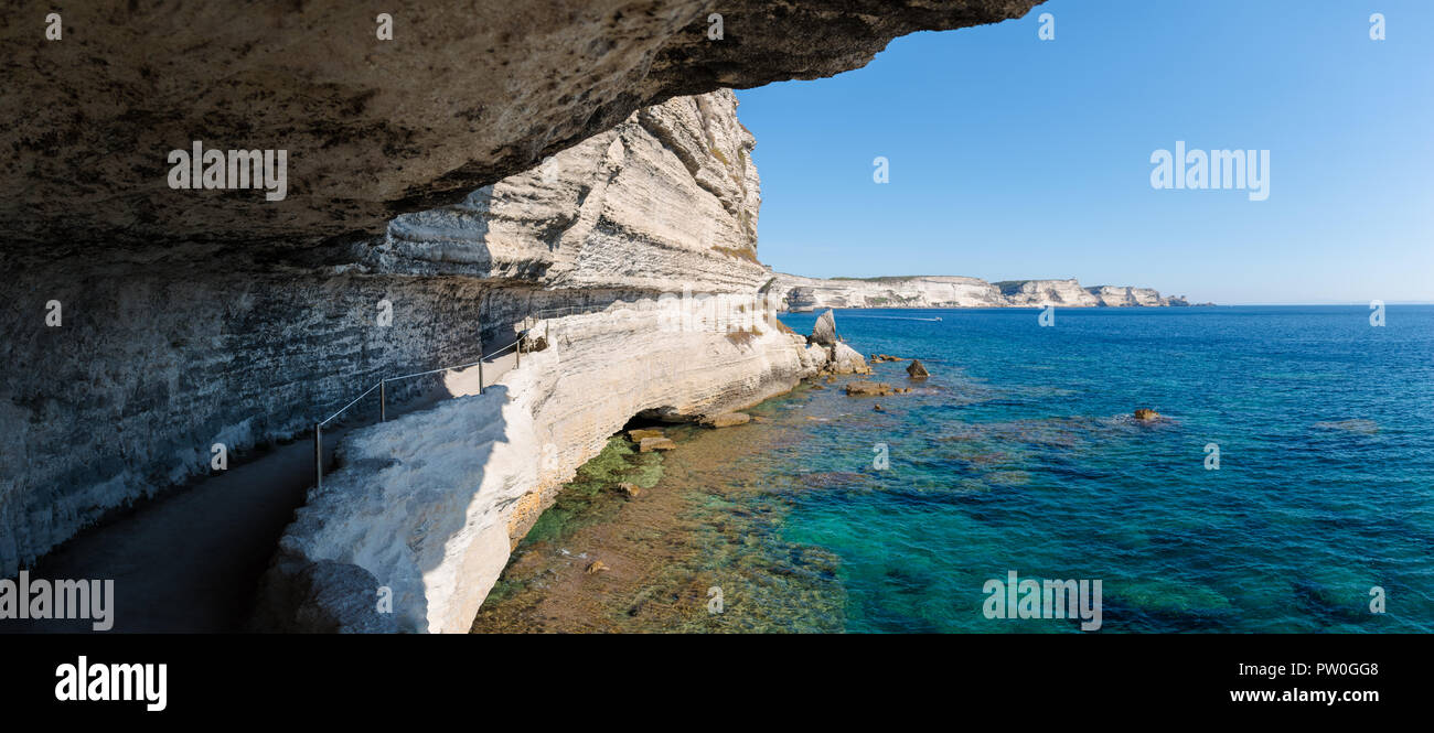 Panoramic view out from a coastal path cut into the side of a white limestone chalk cliff which leads to the King of Aragon staircase in Bonifacio. Stock Photo