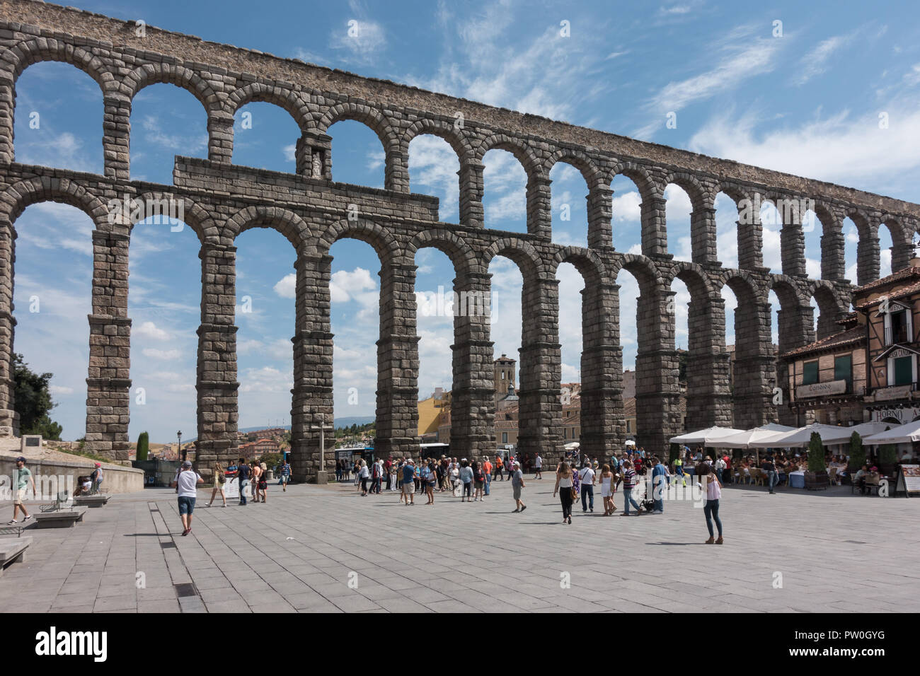 Dramatic, ancient Roman Aqueduct towers over plaza in Segovia, a must-see marvel of engineering in Spain, tourists visit. Stock Photo