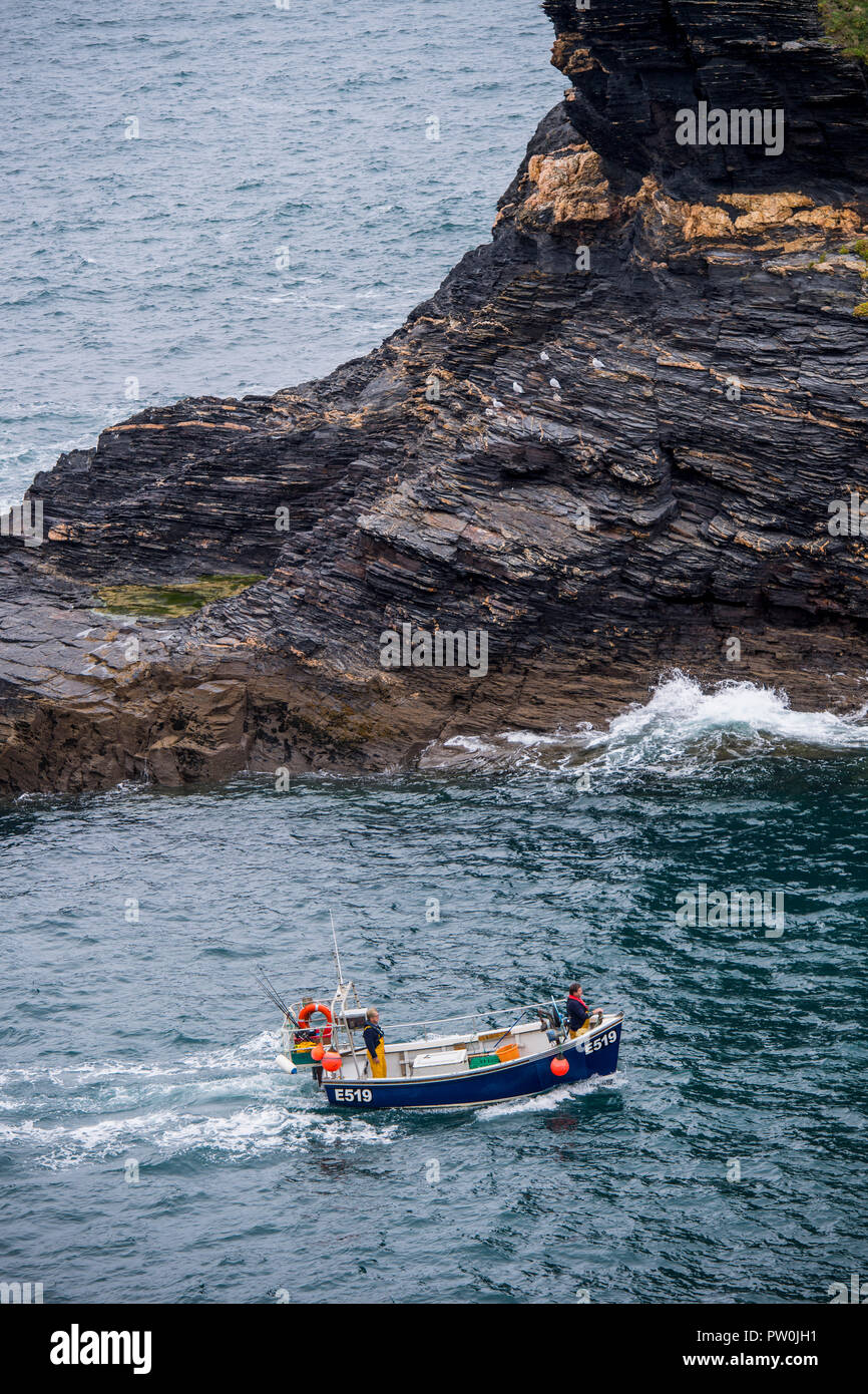 Two fishermen in a boat on the sea returning to Boscastle harbour in Cornwall, England, UK Stock Photo