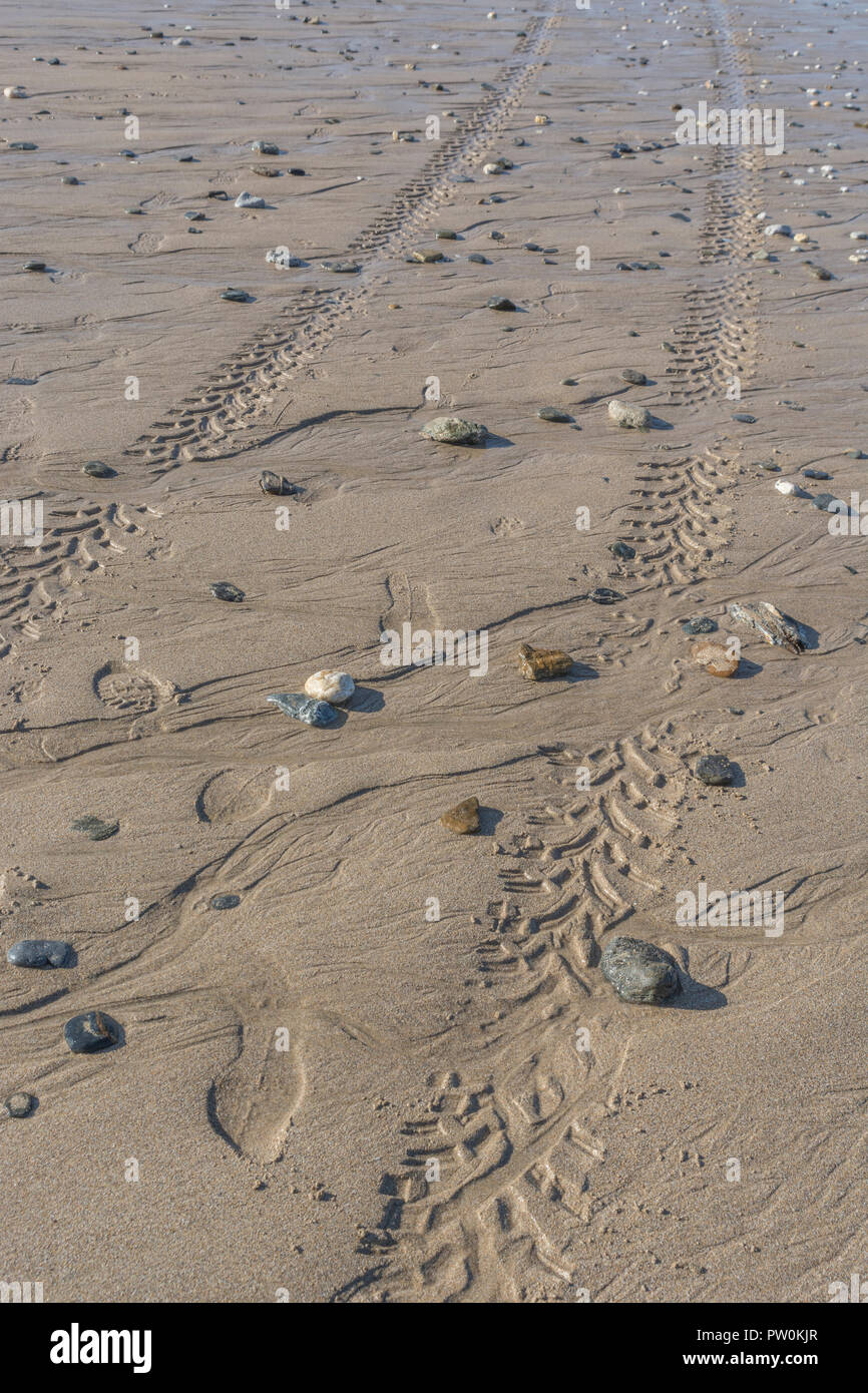 Impressions of tyre tread / tyre marks on wet sandy beach. Stock Photo