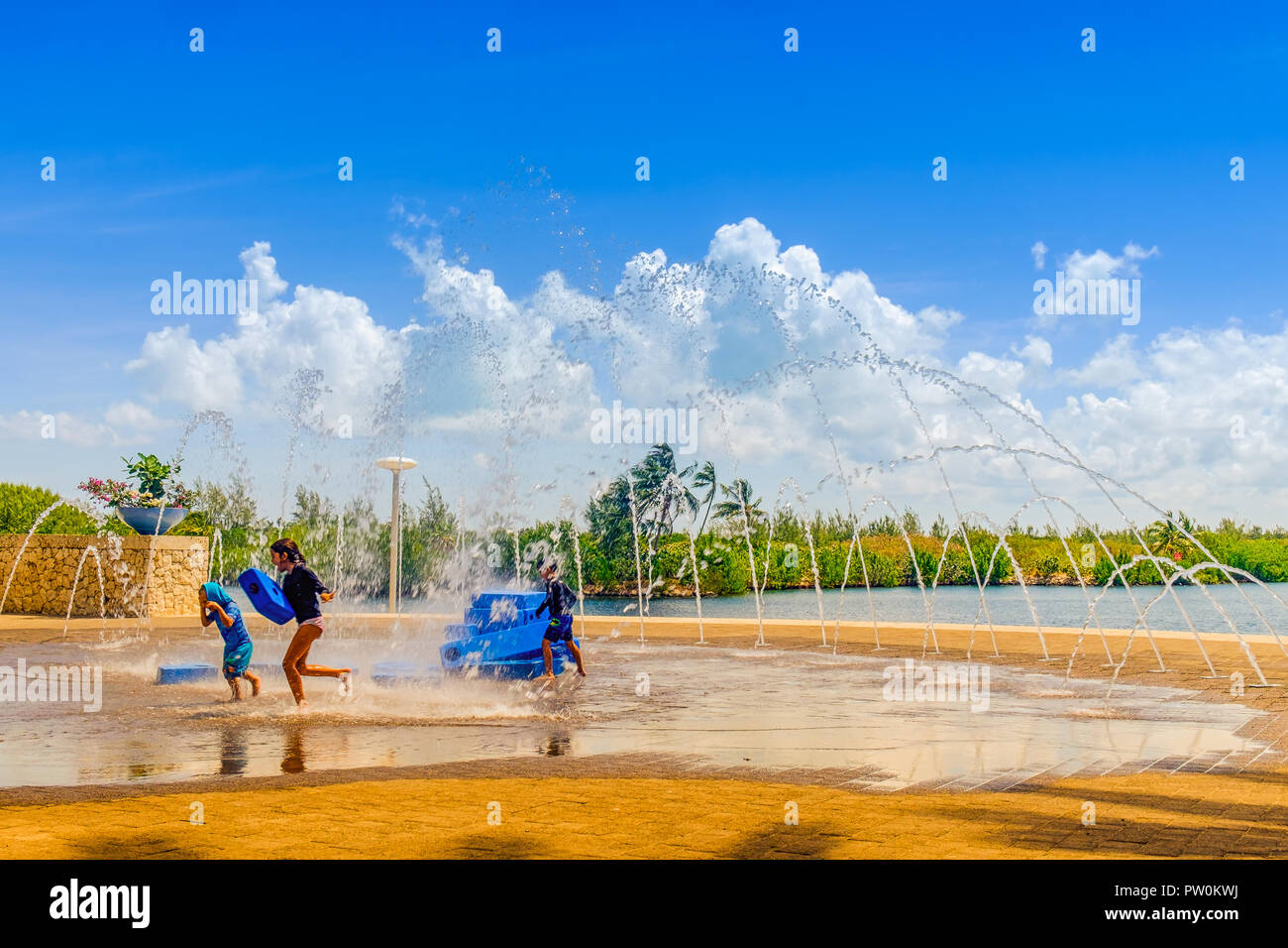 Grand Cayman, Cayman Islands, kids playing by a water fountain on a plaza of Camana Bay a modern waterfront town in the Caribbean Stock Photo
