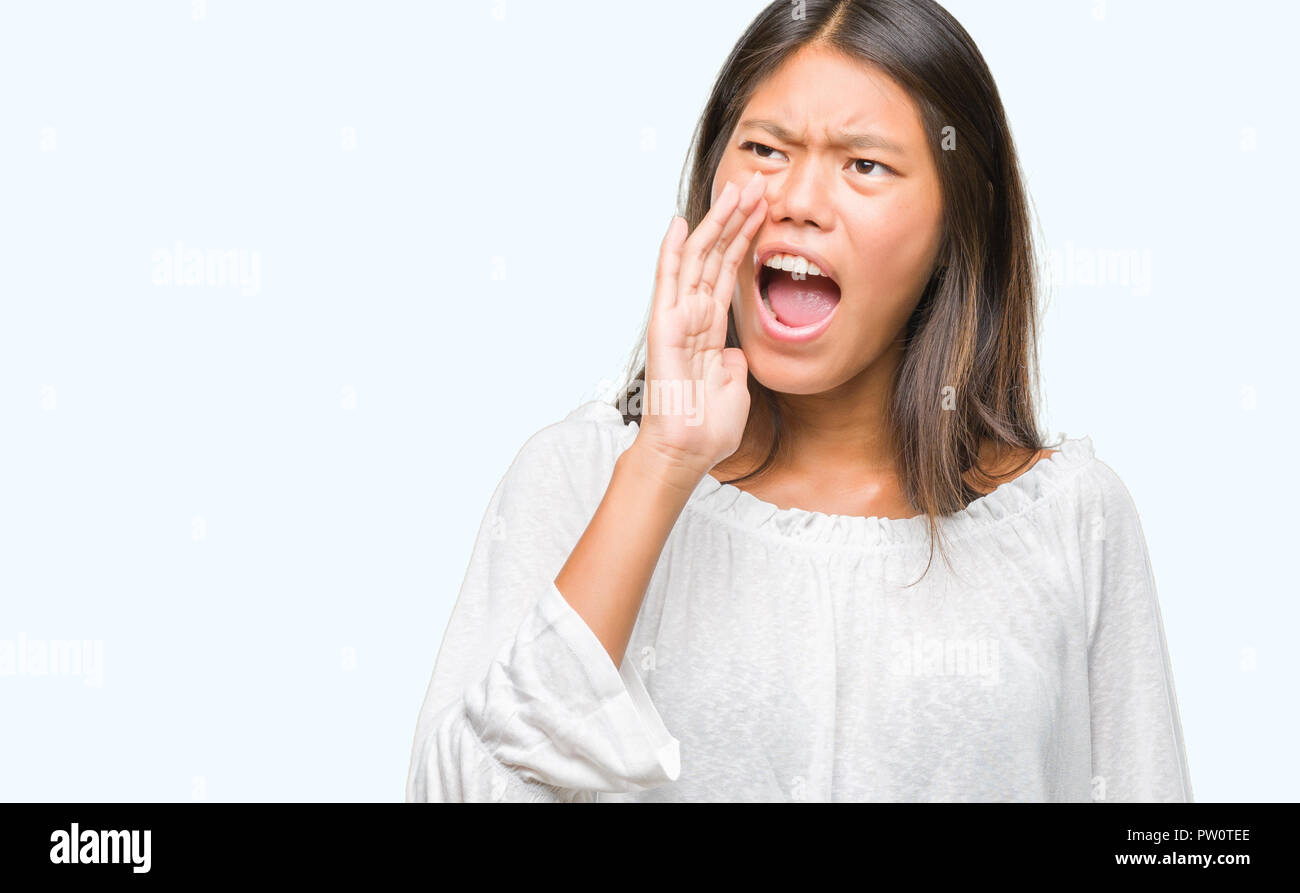 Young asian woman over isolated background shouting and screaming loud ...