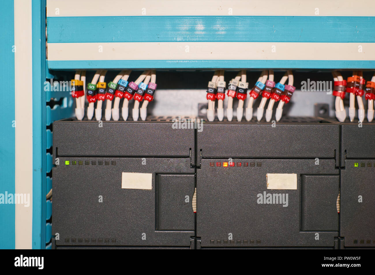 Black controller with connected colored numbered wires. Industrial background. Stock Photo