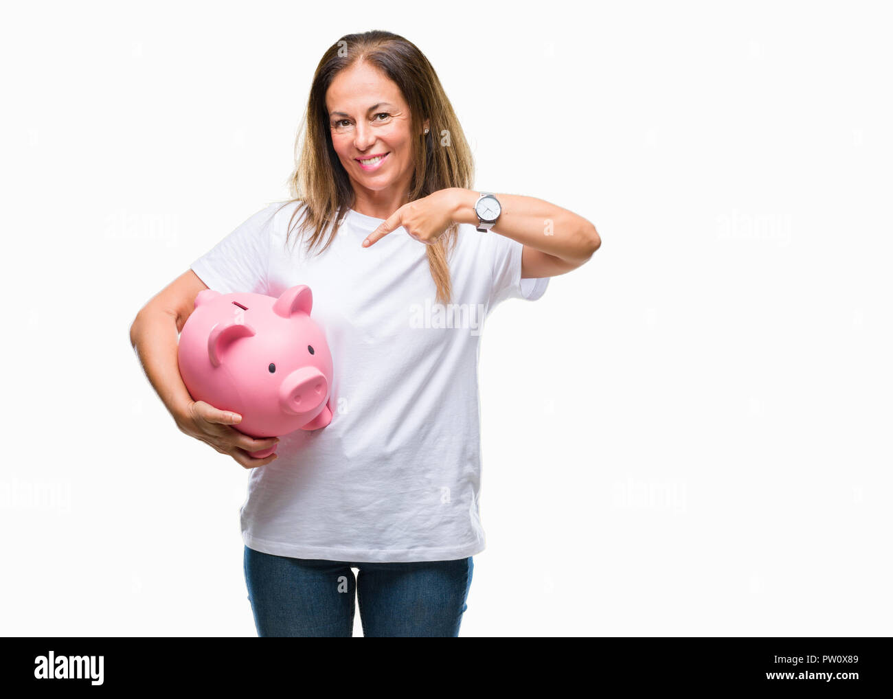 Middle age hispanic woman saving money using piggy bank over isolated background very happy pointing with hand and finger Stock Photo