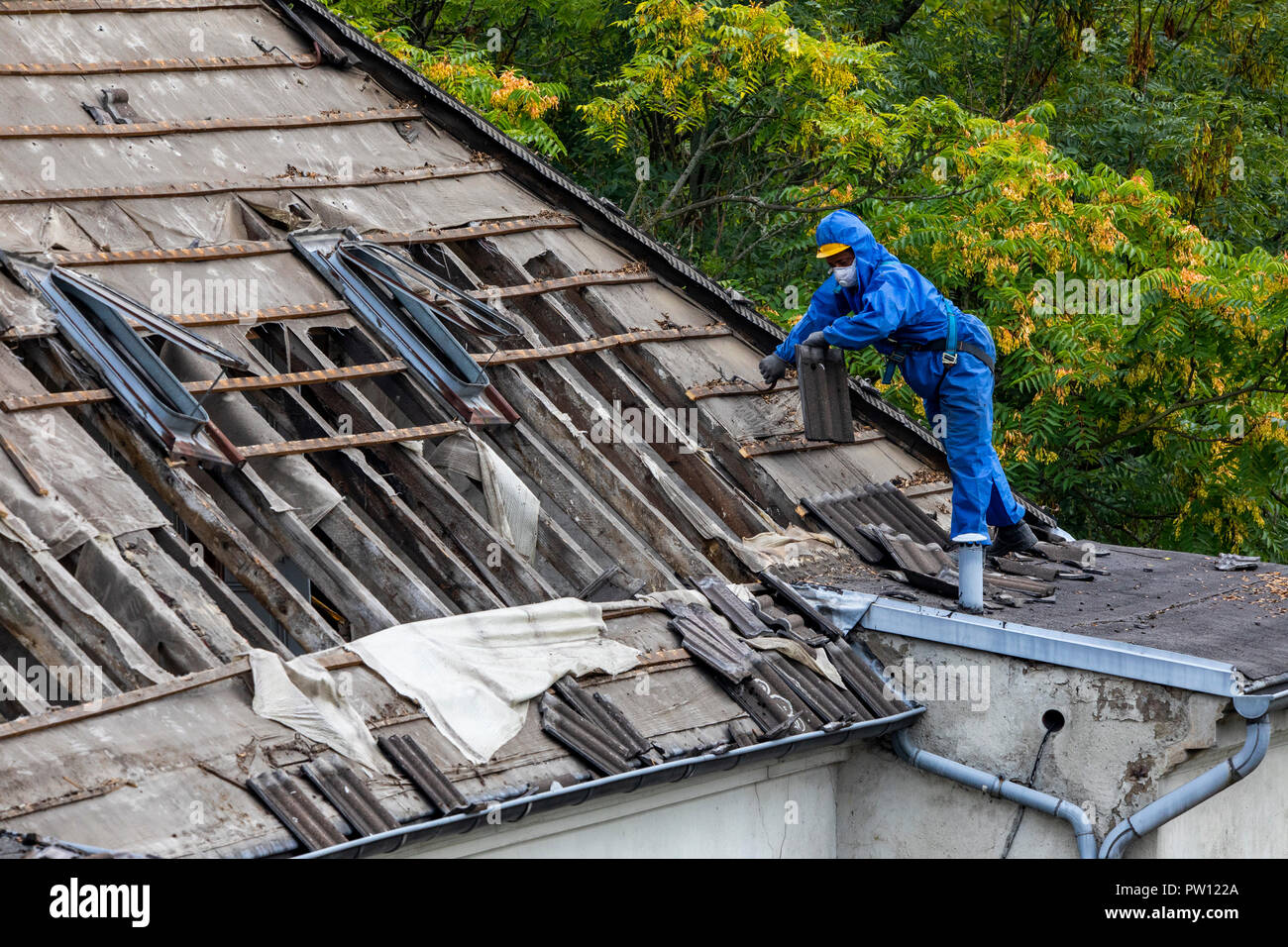 Demolition of an older dwelling house, here new rentable flats are develop, workers in the protective suit disassembled the roof, separates different  Stock Photo