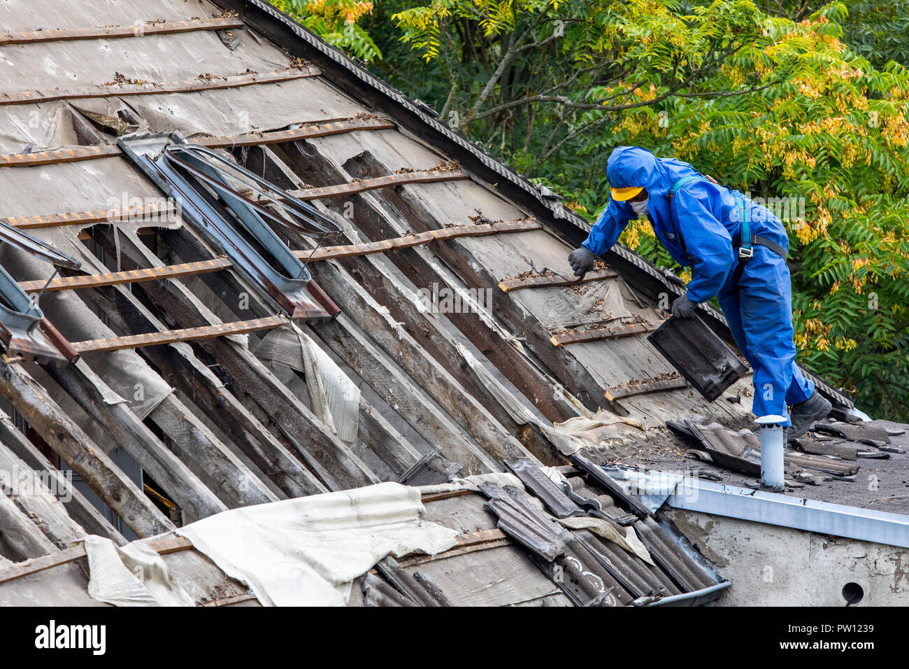 Demolition of an older dwelling house, here new rentable flats are develop, workers in the protective suit disassembled the roof, separates different  Stock Photo