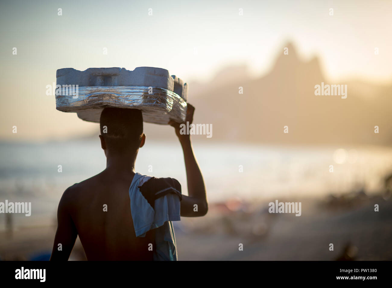 Silhouette of beach vendor carrying an empty tray for caipirinha cocktails at sunset in Rio de Janeiro, Brazil Stock Photo