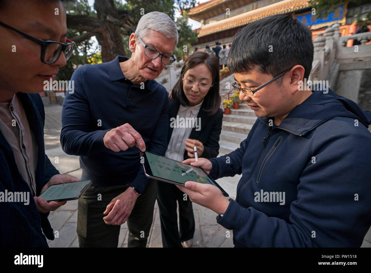 Beijing, China. 10th Oct, 2018. Liu Zhipeng (1st R), one of the founders of Xichuangzhu APP, shows Apple's CEO Tim Cook (2nd L) how to write calligraphy on iPad with Apple Pencil at Beijing Confucian Temple in Beijing, capital of China, on Oct. 10, 2018. Cook paid a visit to Beijing Confucian Temple and the Imperial College on Wednesday. Credit: Cai Yang/Xinhua/Alamy Live News Stock Photo