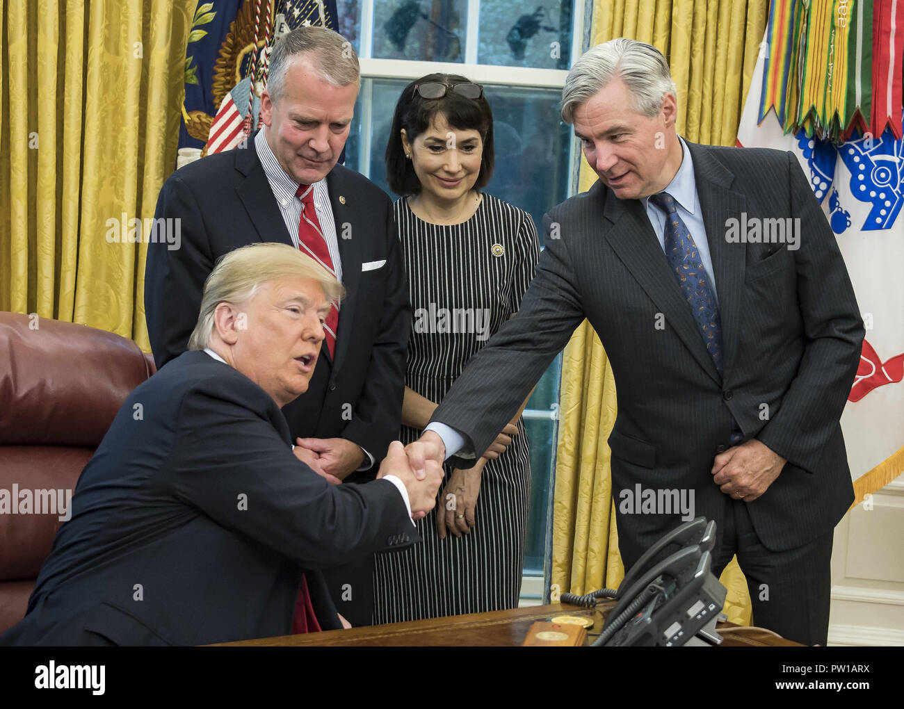 Washington, District of Columbia, USA. 11th Oct, 2018. United States President Donald J. Trump, left, shakes hands with US Senator Sheldon Whitehouse (Democrat of Rhode Island), right, prior to signing S. 3508, the 'Save Our Seas Act of 2018'' in the Oval Office of the White House in Washington, DC on Thursday, October 11, 2018. Looking on are US Senator Dan Sullivan (Republican of Alaska), center left, and Julie Fate, wife of Senator Sullivan, center right Stock Photo