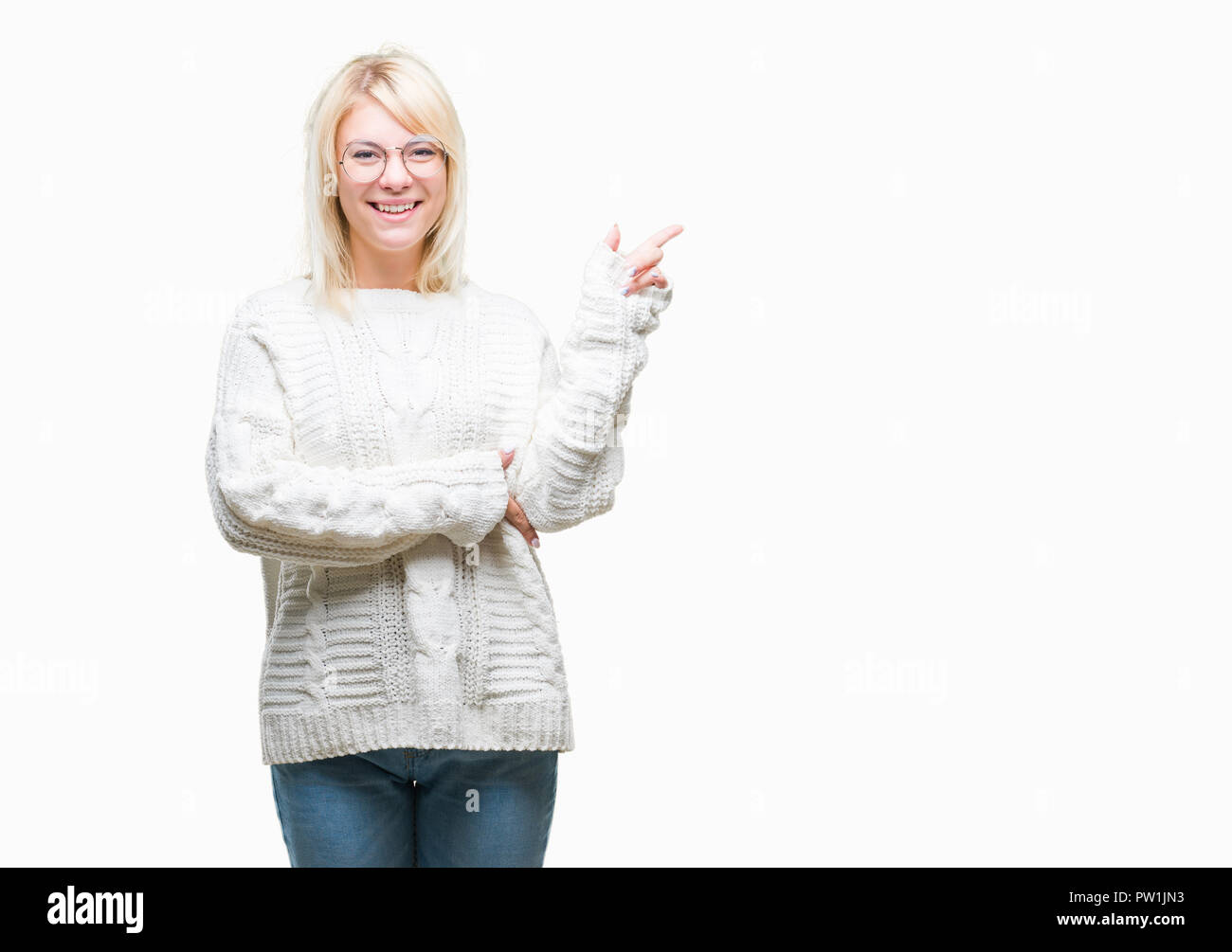 Young beautiful blonde woman wearing winter sweater and glasses over isolated background with a big smile on face, pointing with hand and finger to th Stock Photo