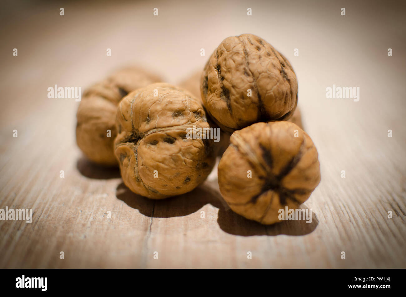 Walnuts on a wooden kitchen table .  grouped up together, close up with bokeh effect in the background. Usable for a picture on the wall in a restaura Stock Photo