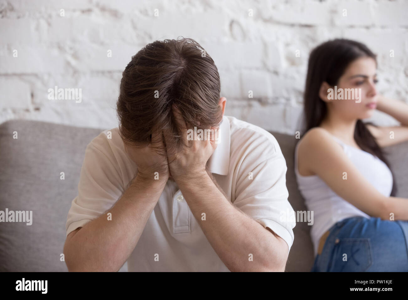 Unhappy young man and woman in quarrel sitting on couch Stock Photo