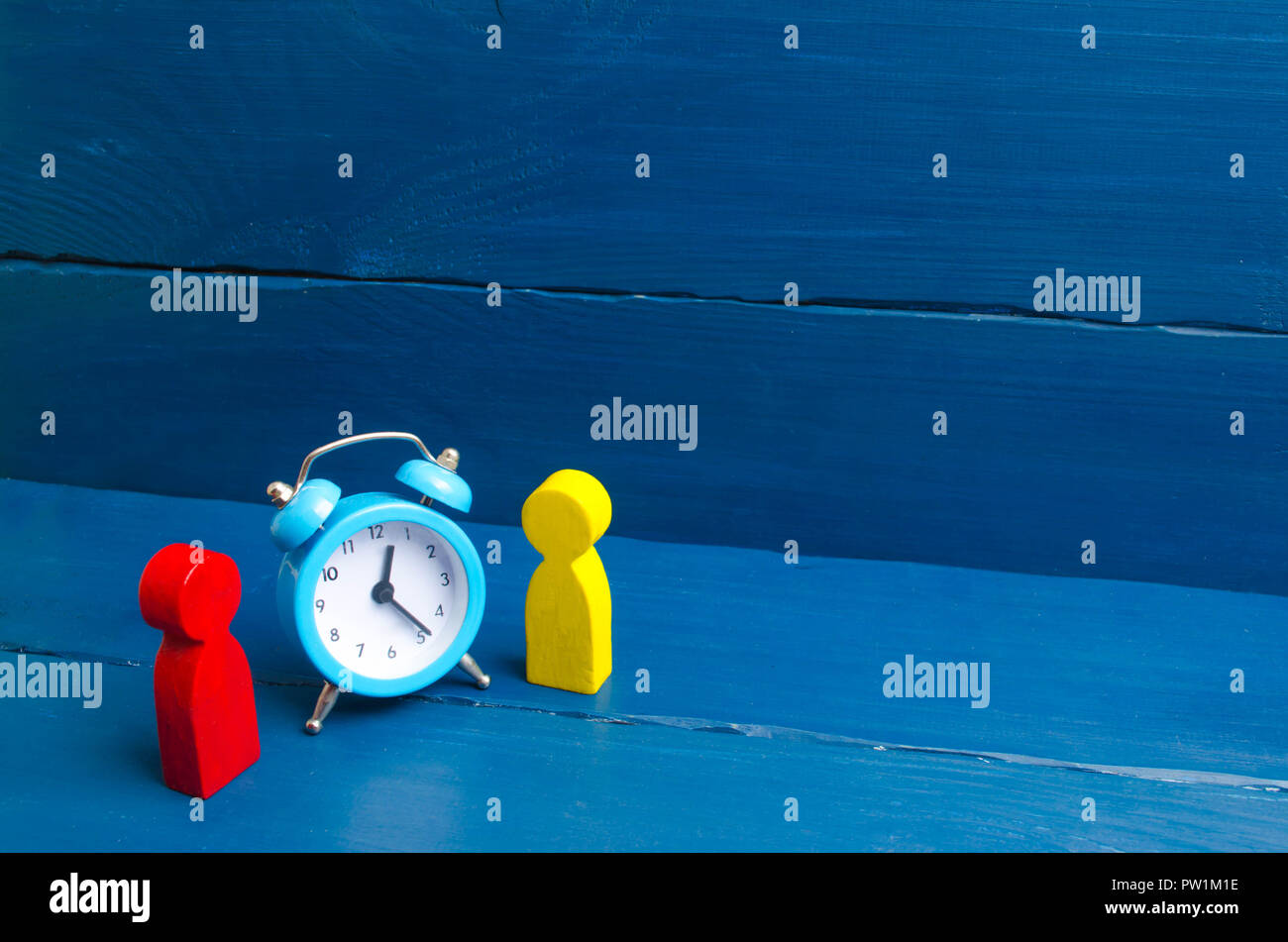 Two men stand near the blue alarm clock and talk. The concept of waiting for a meeting, a date
