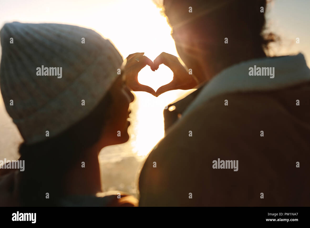 Rear view close up of man and woman making heart with hands against ...