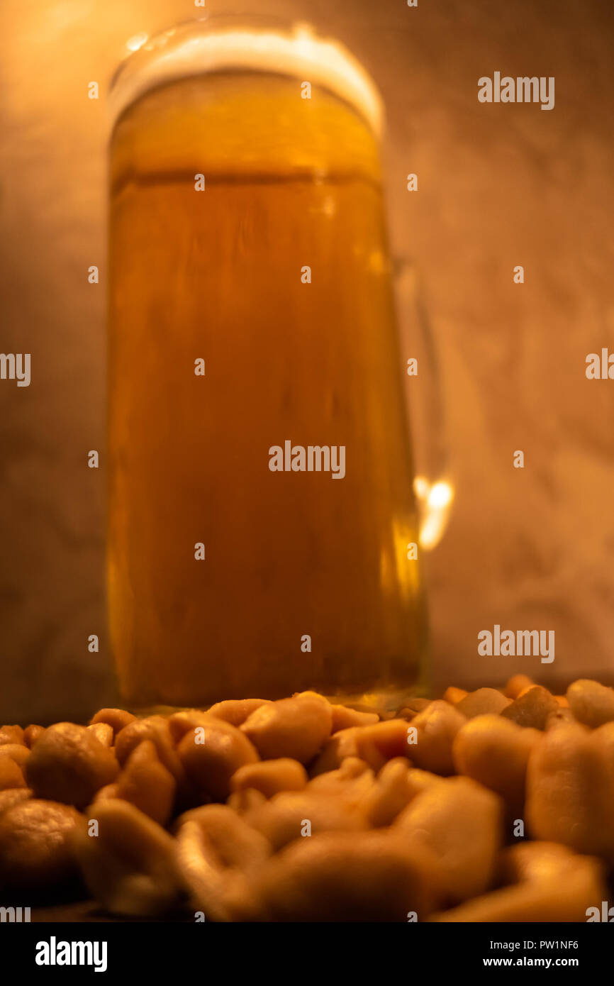 glass of light cold frothy beer, nuts on an old wooden table. Stock Photo