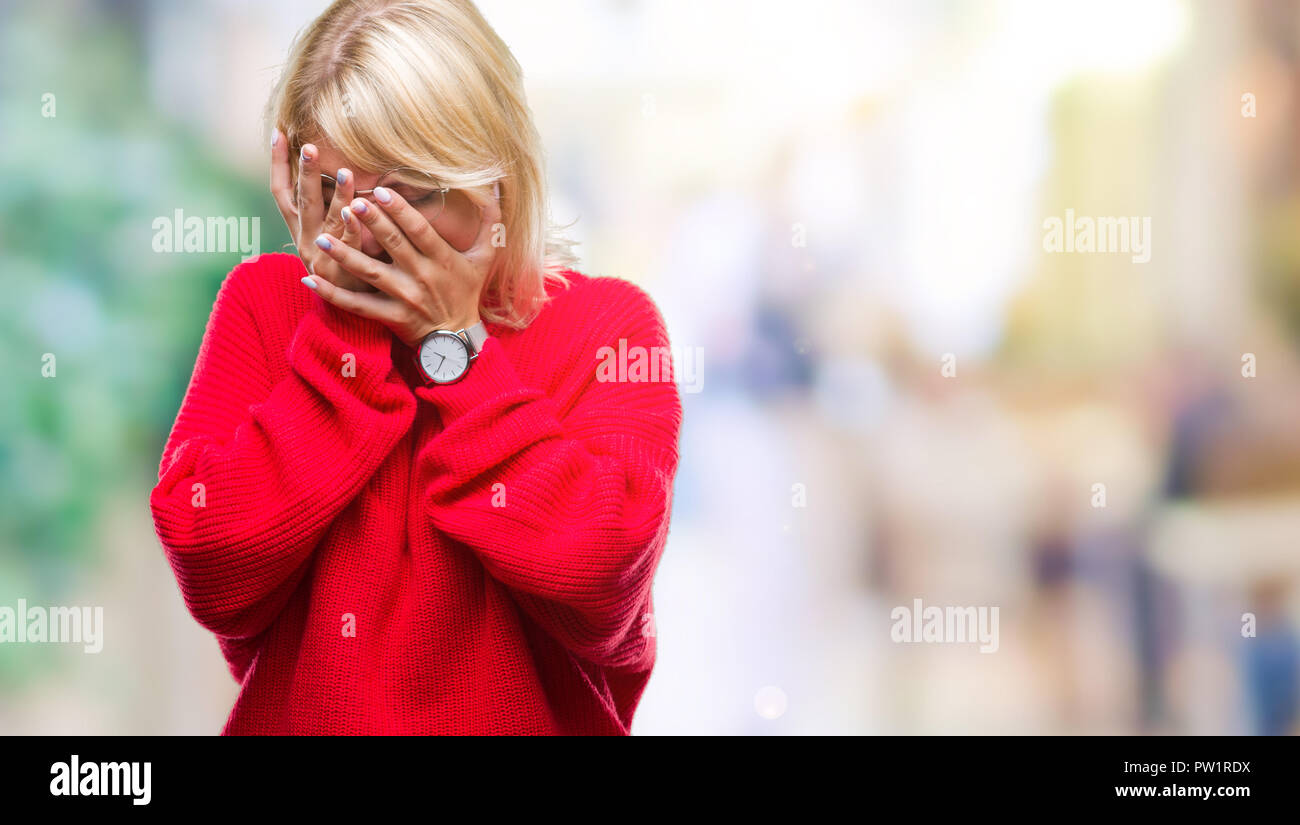 Young beautiful blonde woman wearing sweater and glasses over isolated background with sad expression covering face with hands while crying. Depressio Stock Photo