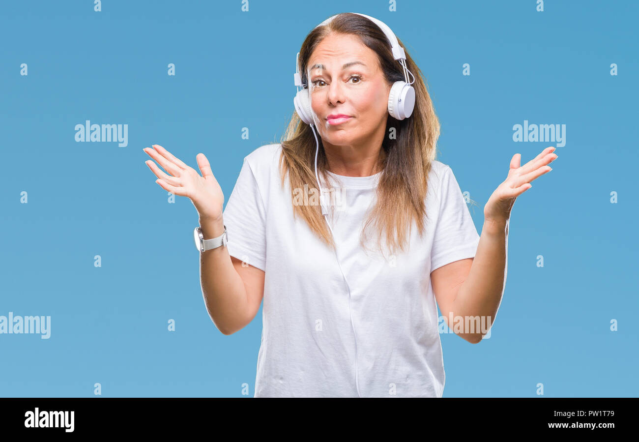 Middle age hispanic woman listening to music wearing headphones over ...