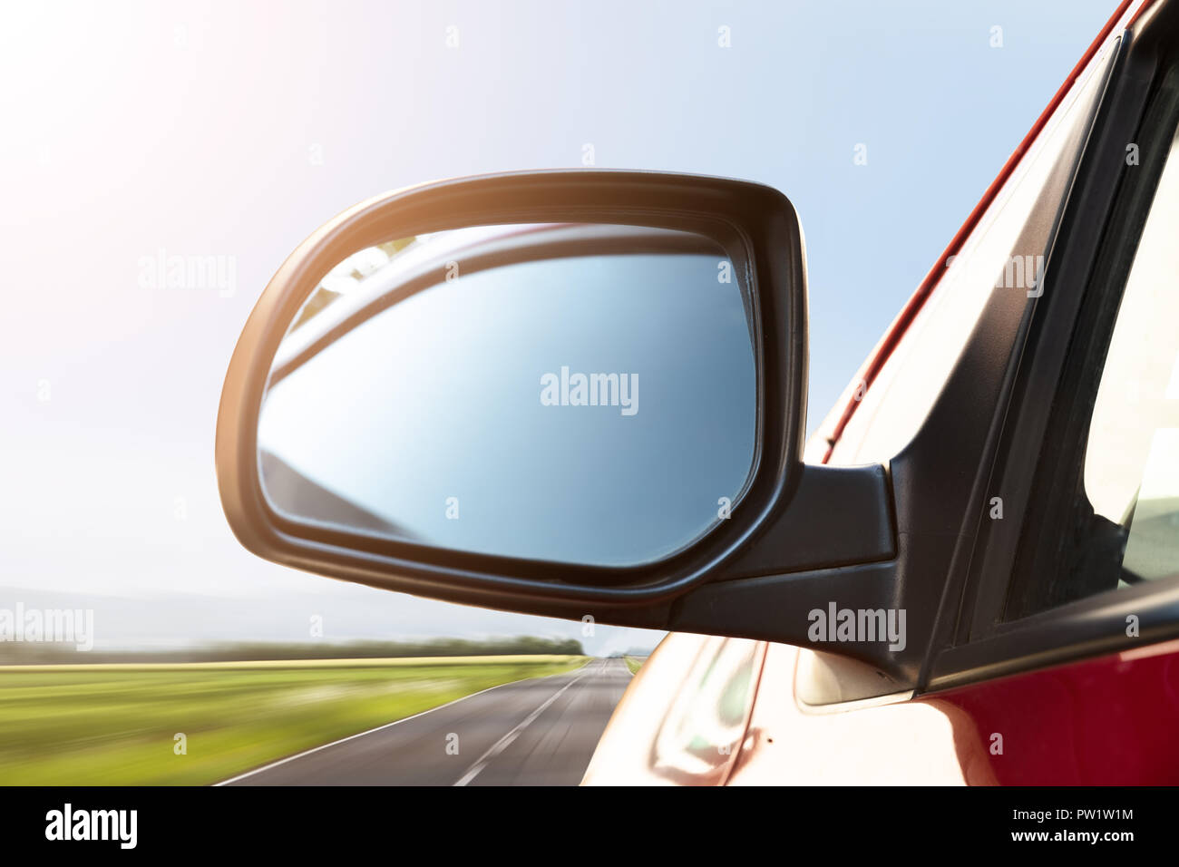 Rear View Mirror Of A Car Driving On Street Stock Photo