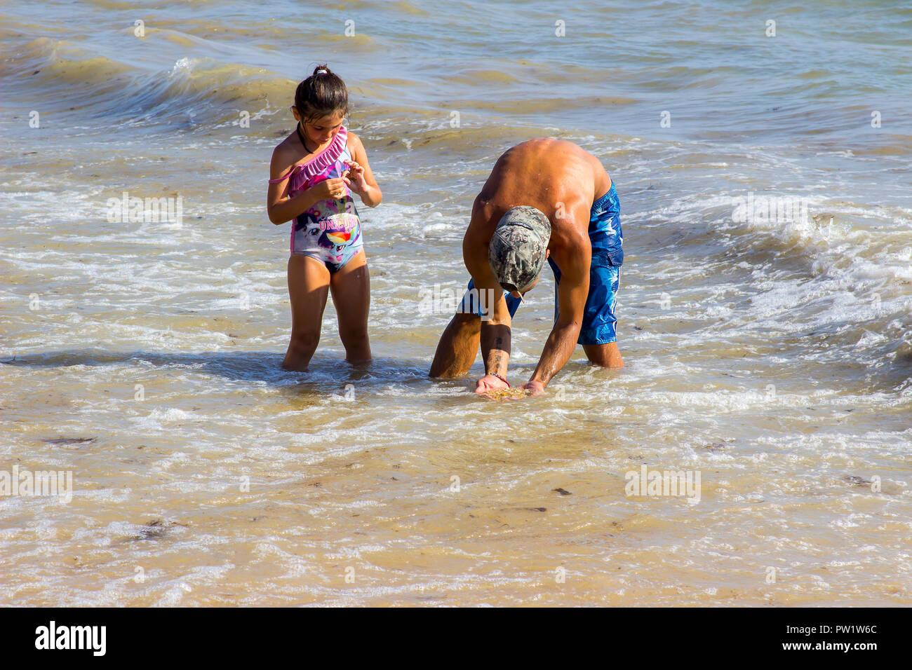 29 September 2018 A father and young daughter play together in the surf on a beach in Albuferia on the Algarve inPortugal on a beautiful sunny afterno Stock Photo