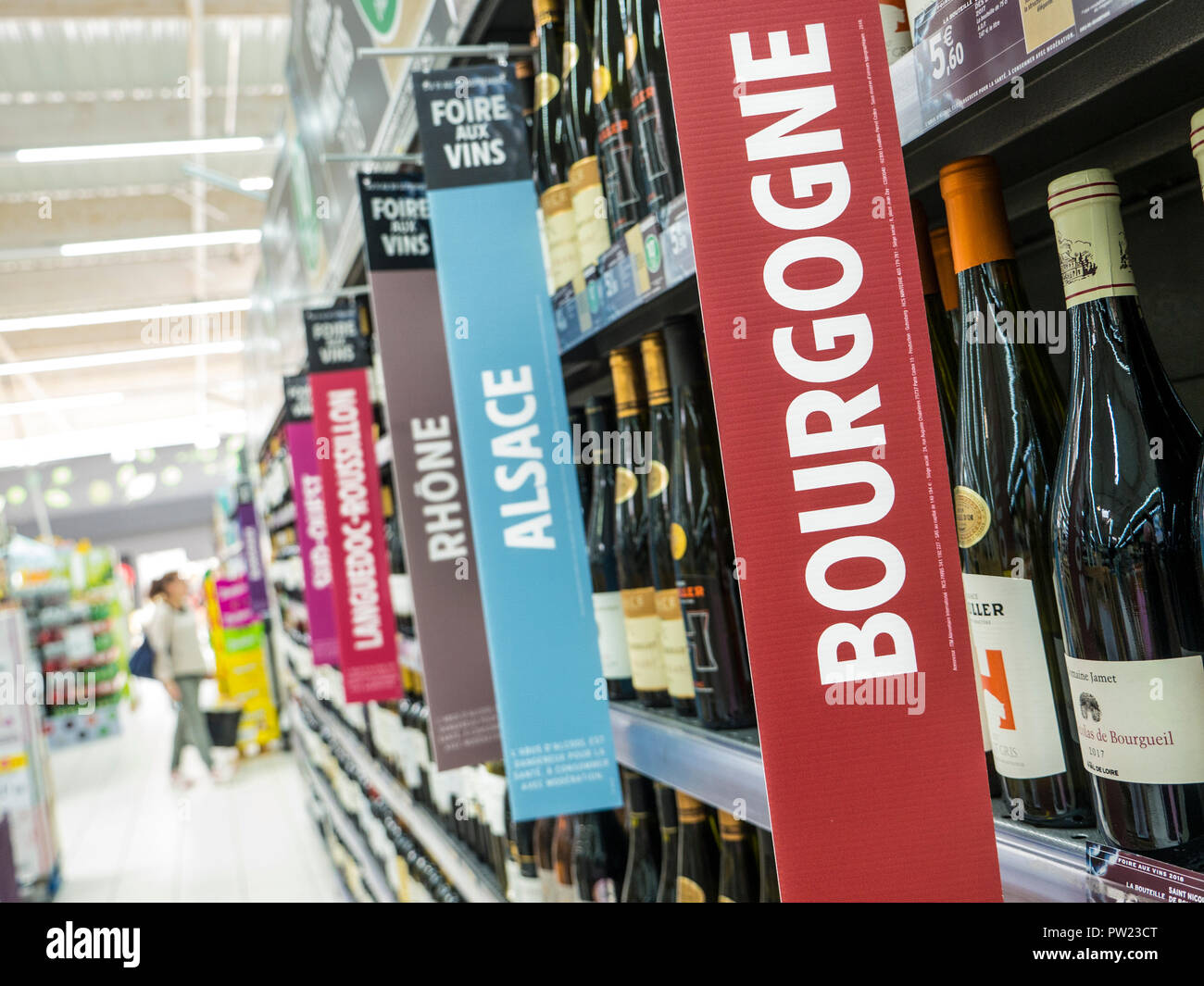 French wine varieties banners bottles supermarket aisle & BOURGOGNE sign wine display feature French supermarket, woman shopper behind Brittany France Stock Photo