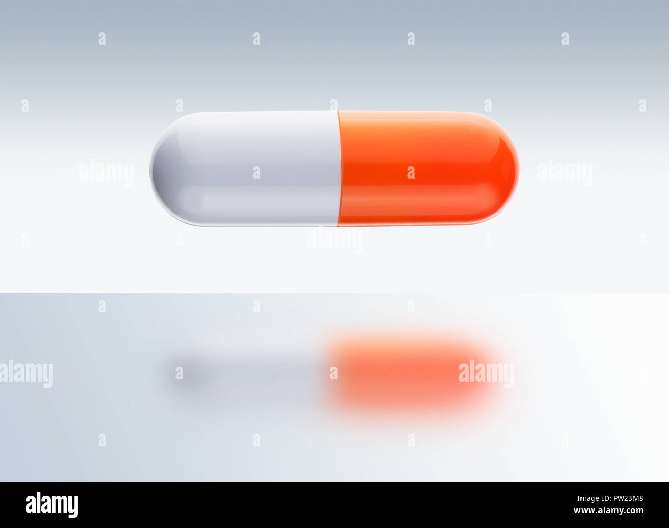 A Orange and White Pill Suspended in Mid Air Stock Photo