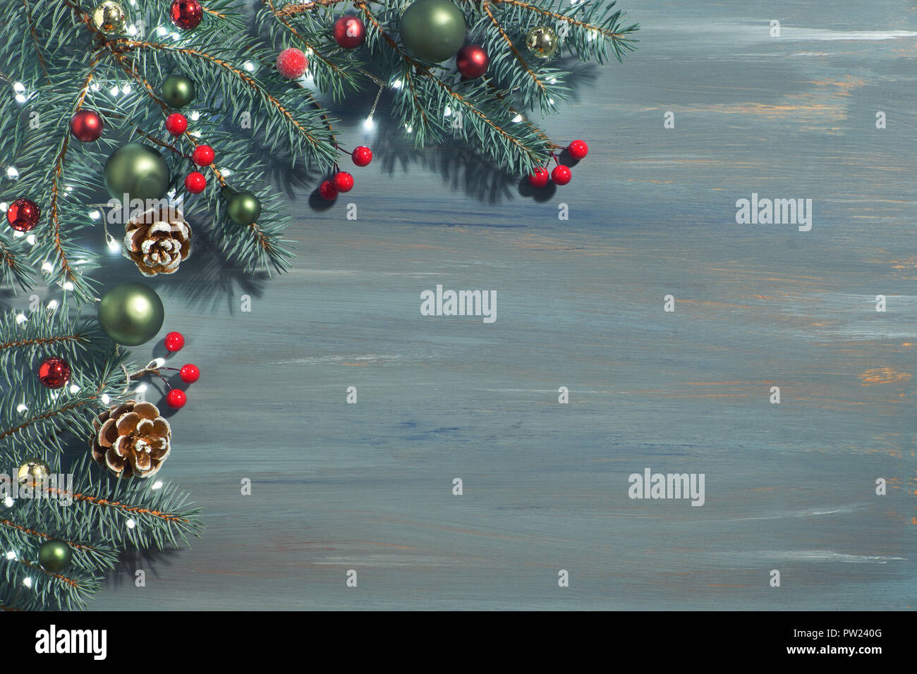 Christmas background with fir twigs, red berries, cones and Xmas lights ...