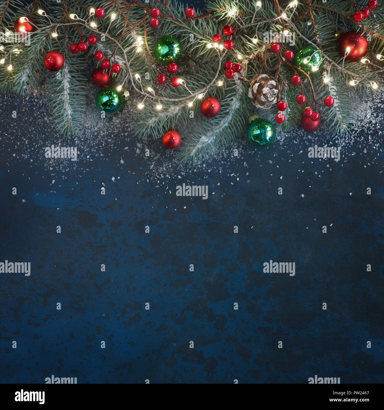 Christmas background with fir twigs, red berries, cones and Xmas lights ...