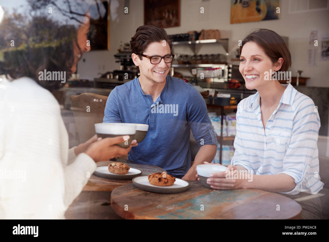 Three friends talking and drinking coffee at a coffee shop Stock Photo
