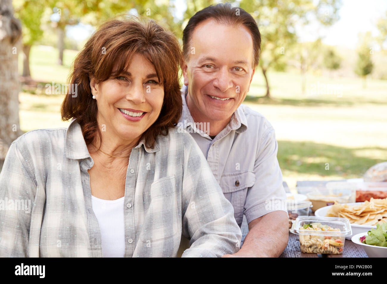 Senior couple sitting at picnic table in a park Stock Photo