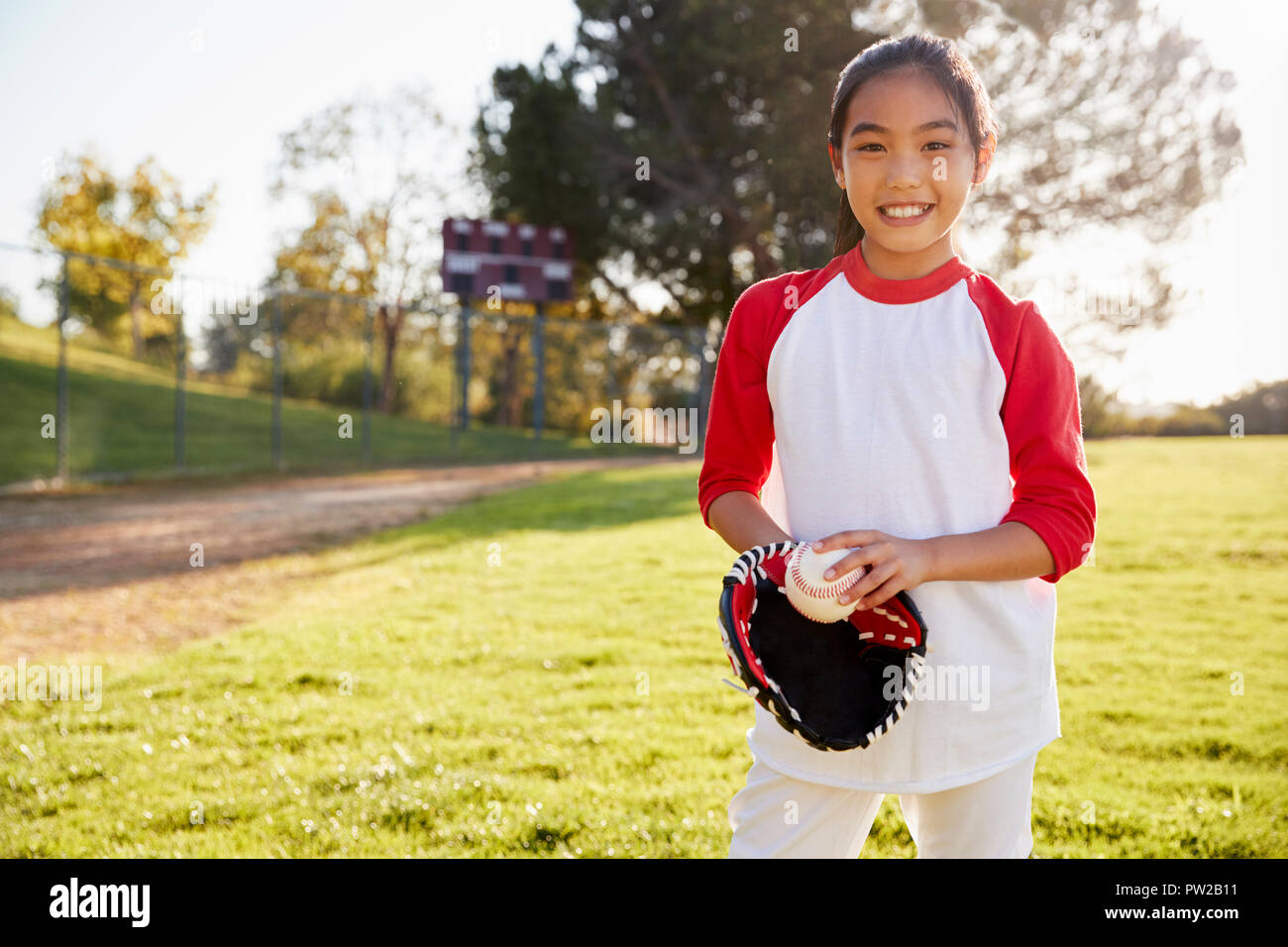 Chinese schoolgirl holding baseball and mitt smiling Stock Photo