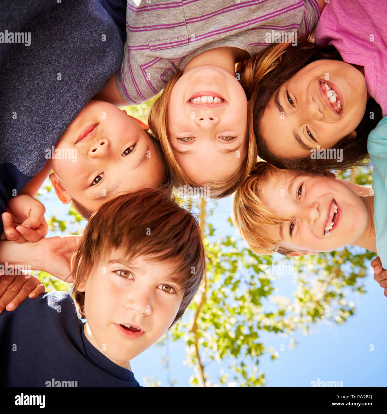 Five schoolchildren standing in a circle and smiling Stock Photo