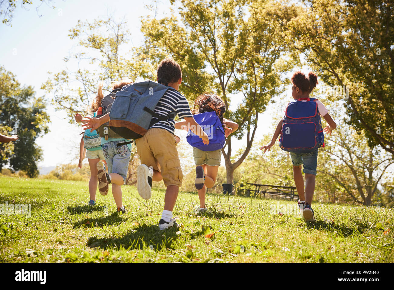 Five school kids running in a field, back view, close up Stock Photo