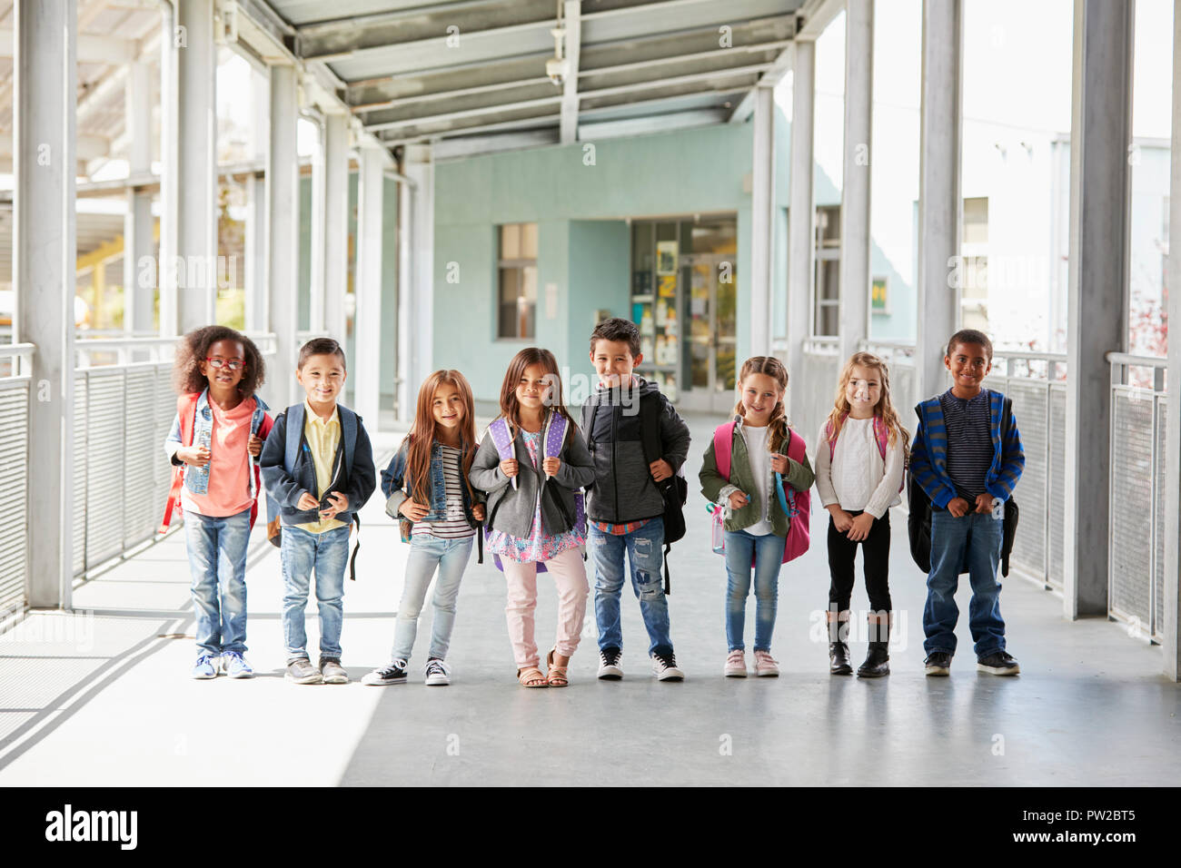 Elementary school class standing in corridor with their bags Stock Photo