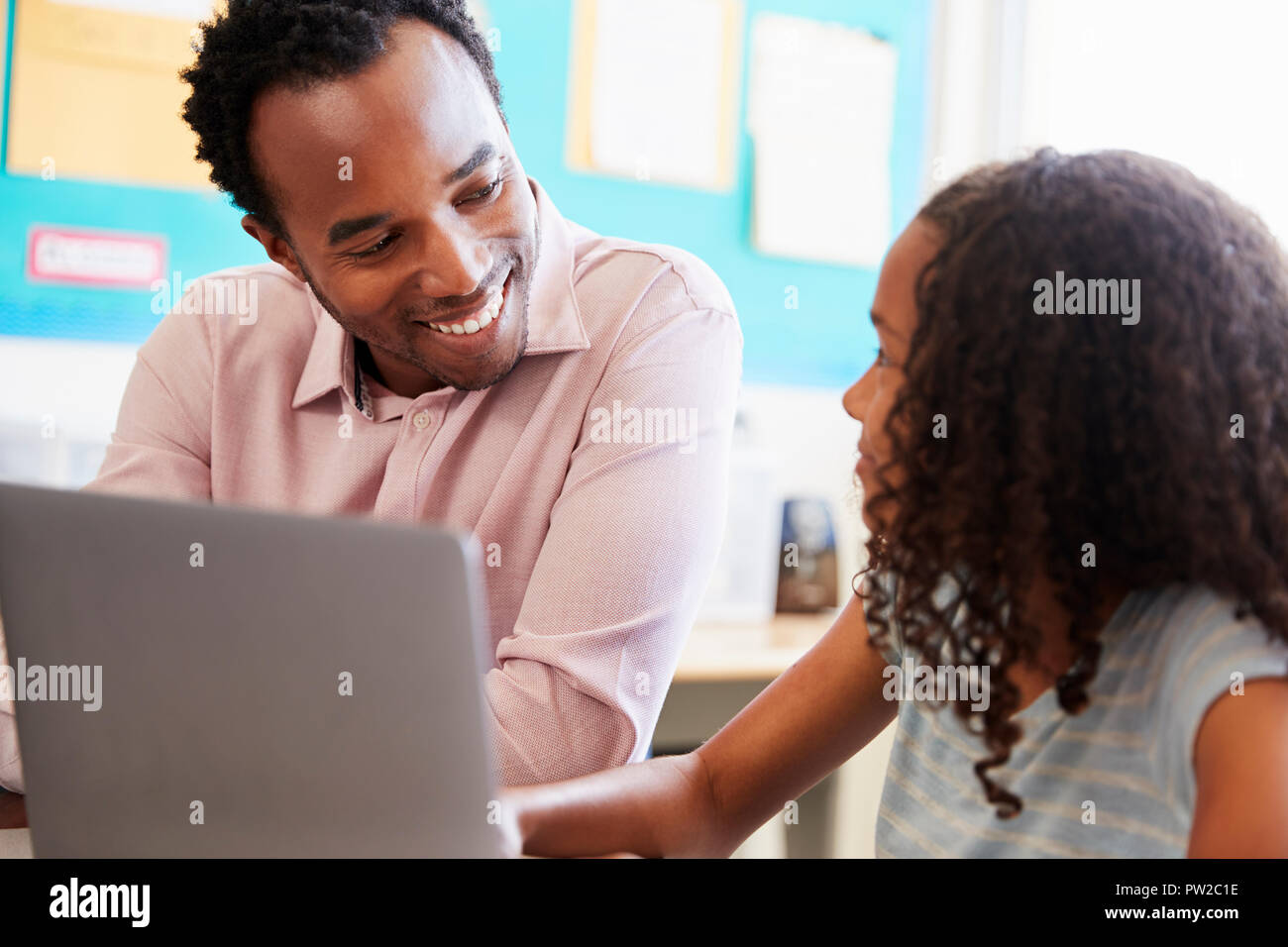 Teacher working with elementary school girl at computer Stock Photo - Alamy